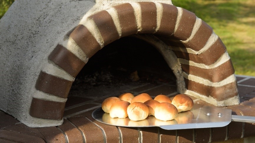 Versgebakken brood uit pizzaoven scheppen